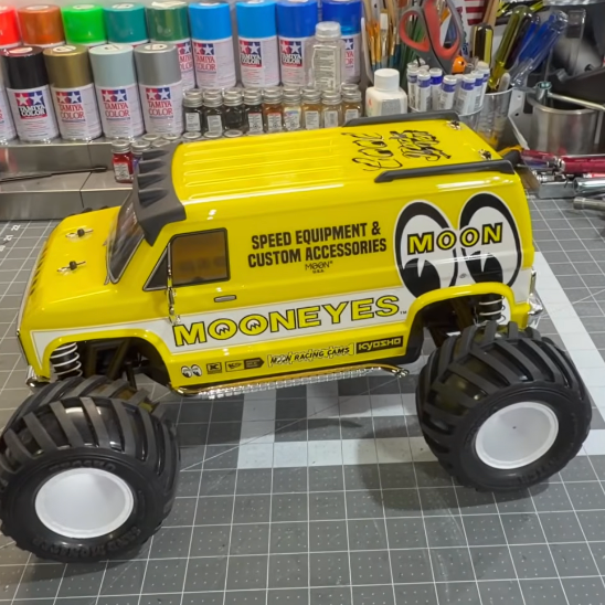 Kyosho Fazer Mk2 Mad Van MOONEYES Edition 1/10 RC truck with yellow custom van body and white wheels on a hobby workbench