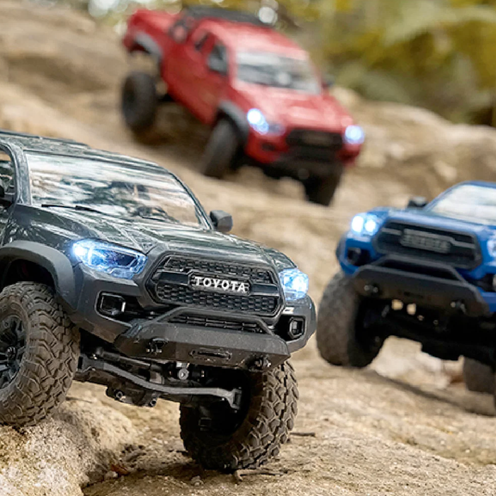 FMS FCX24M Toyota Tacoma RTR review showing three licensed hard-body micro trail trucks on rocky terrain