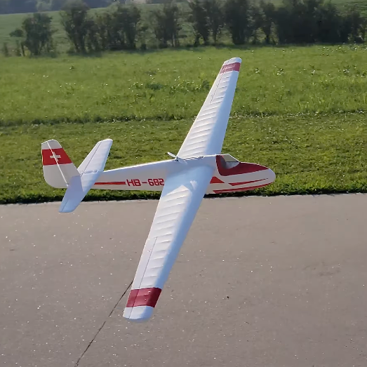HobbyKing Hall Cherokee V2 1700mm glider flying low over a grass field with retractable motor pod