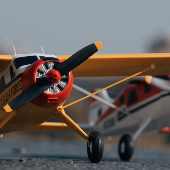 FMS 800mm Beaver PNP RC bush plane on the runway in a front three-quarter view, showing the high wing, tundra-style landing gear, and propeller spinner