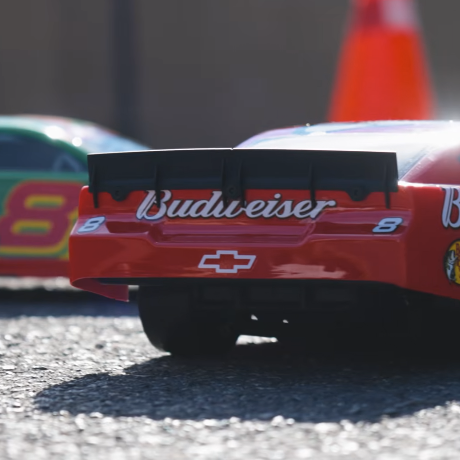 Losi Asphalt Late Model GROM RC car racing on asphalt driveway next to Losi NASCAR model